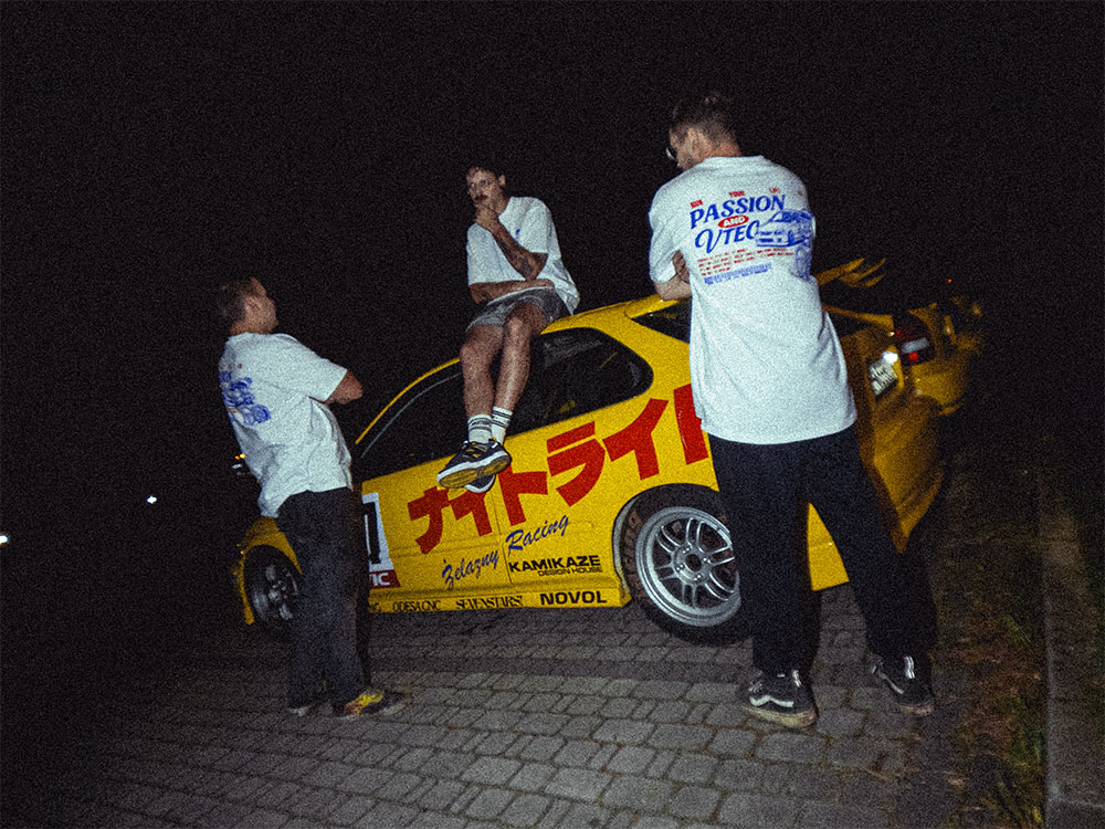 Ekipa NIGHTRIDE nocą przy żółtej Silvii z oznaczeniem NIGHTRIDE na drzwiach.